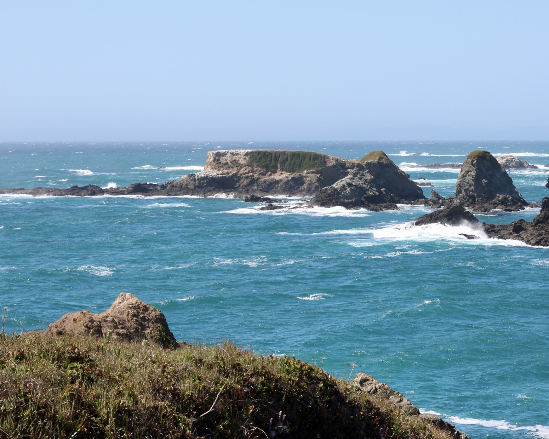 Turquoise Mendocino coastline with sea stacks and a distant house