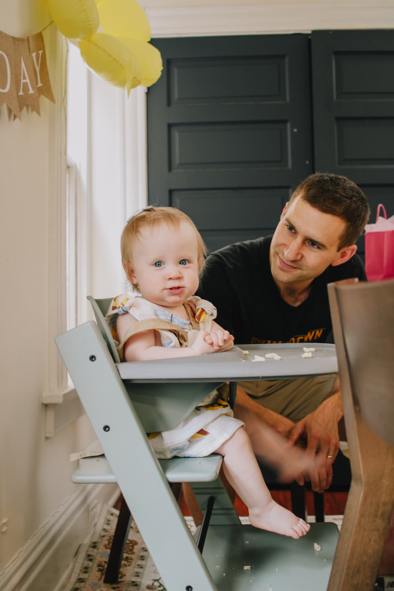 Phoebe in her highchair with her dad under the Happy Bee Day banner