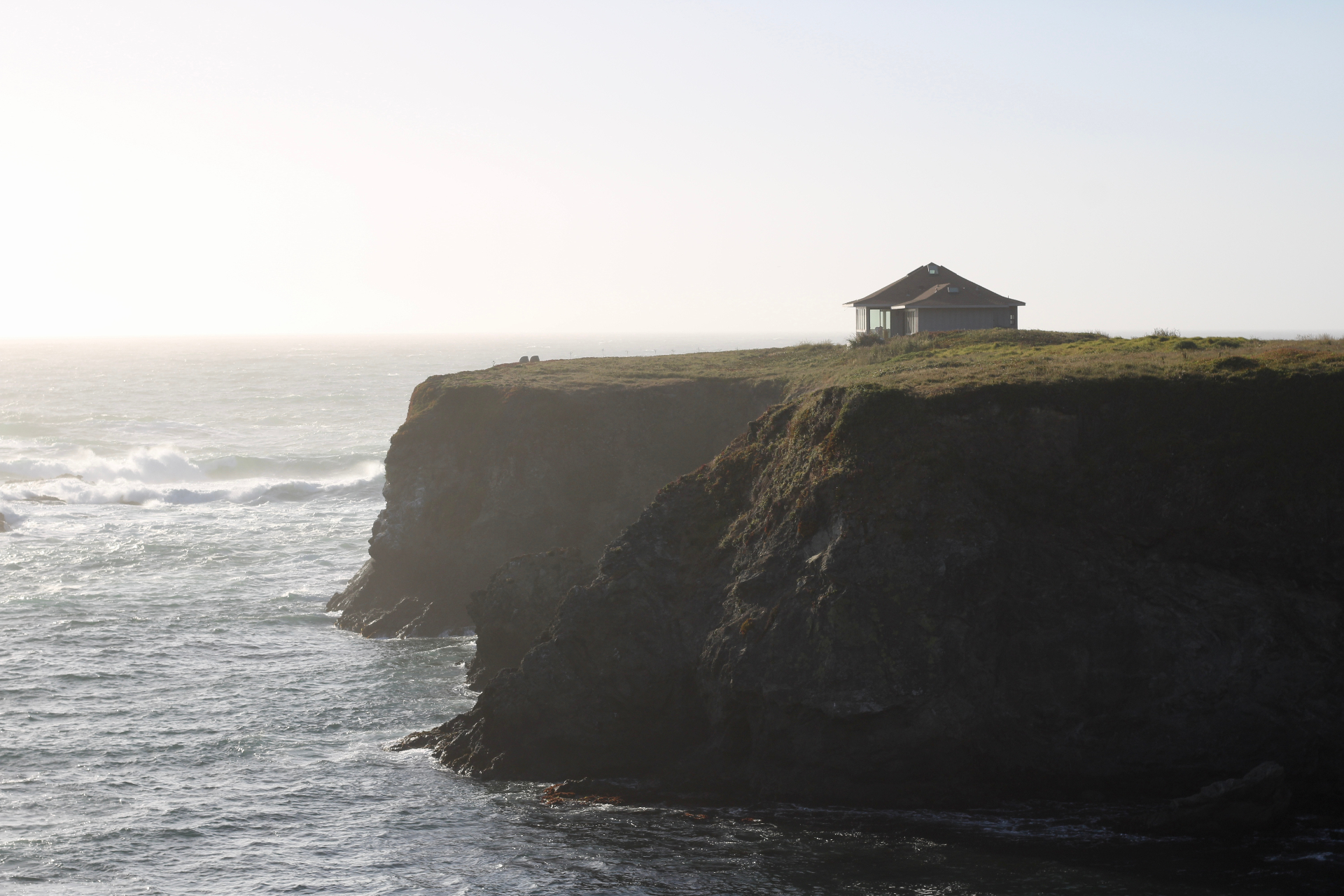 A house on the cliff edge overlooking the Mendocino coast at sunset