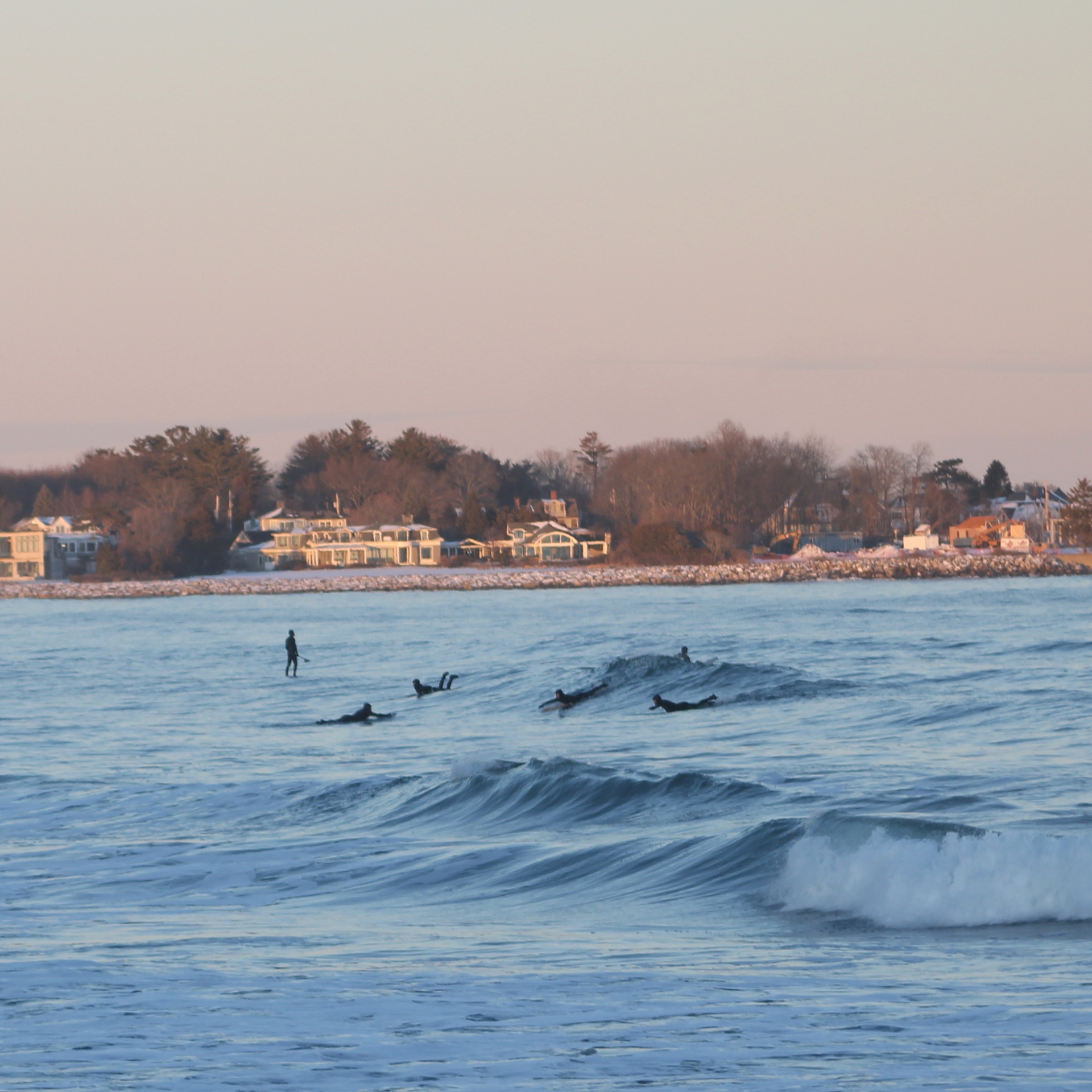Surfers paddling out at Rye, New Hampshire in soft evening light