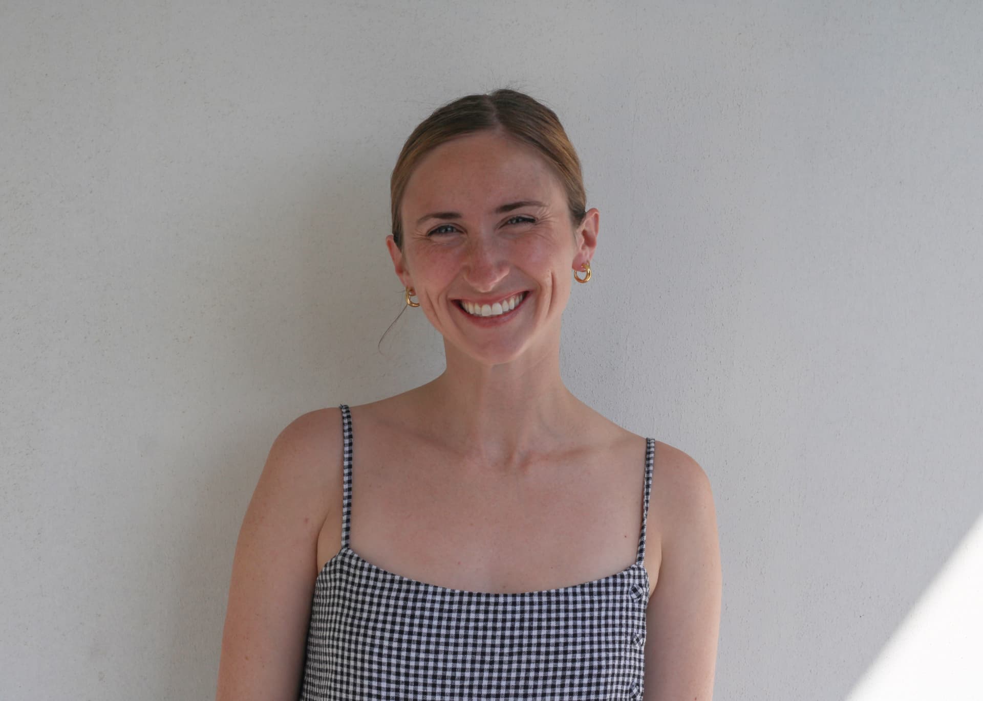 Allison Cross smiling against a white wall