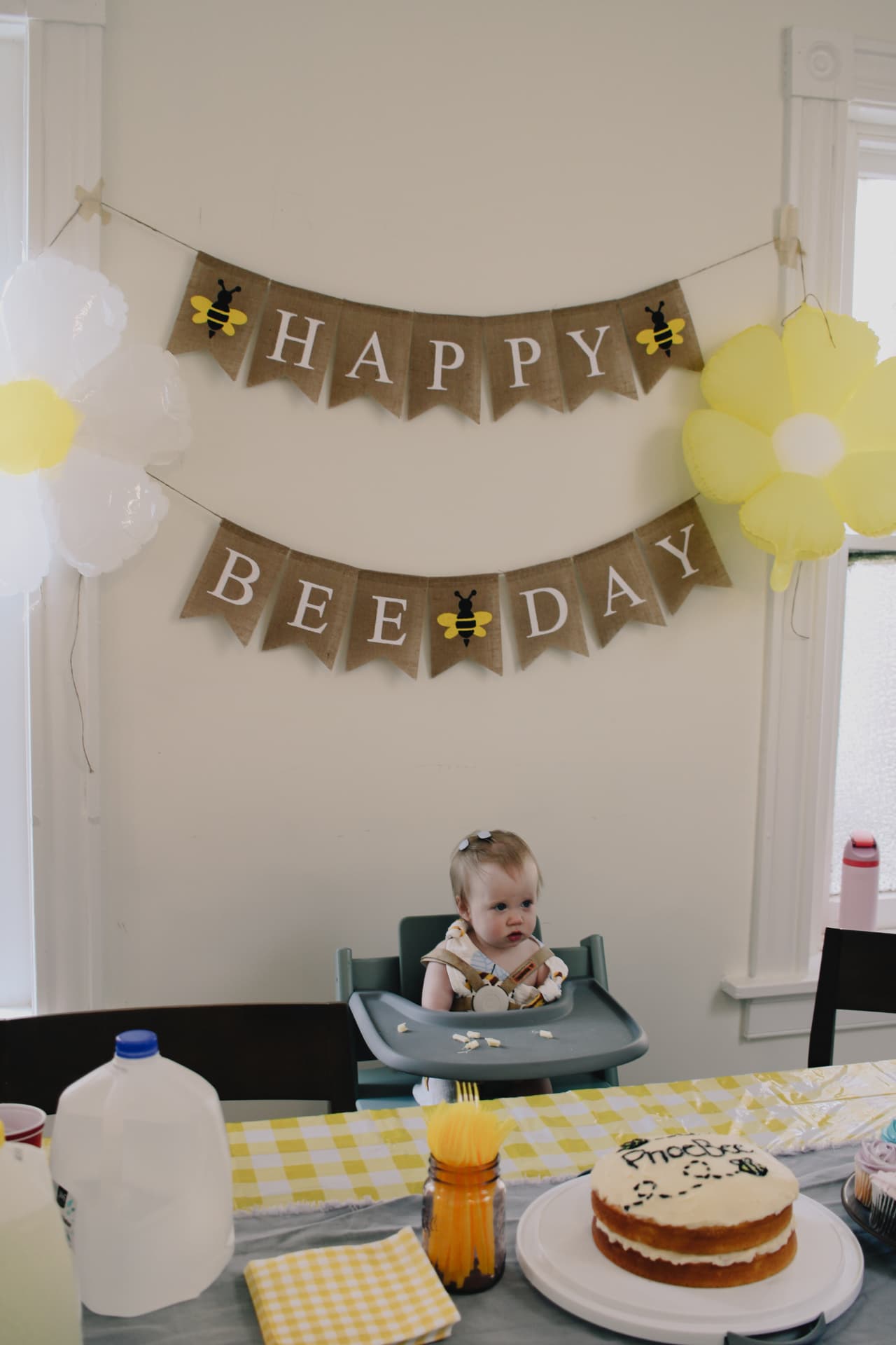 Phoebe in her highchair beneath the Happy Bee Day banner