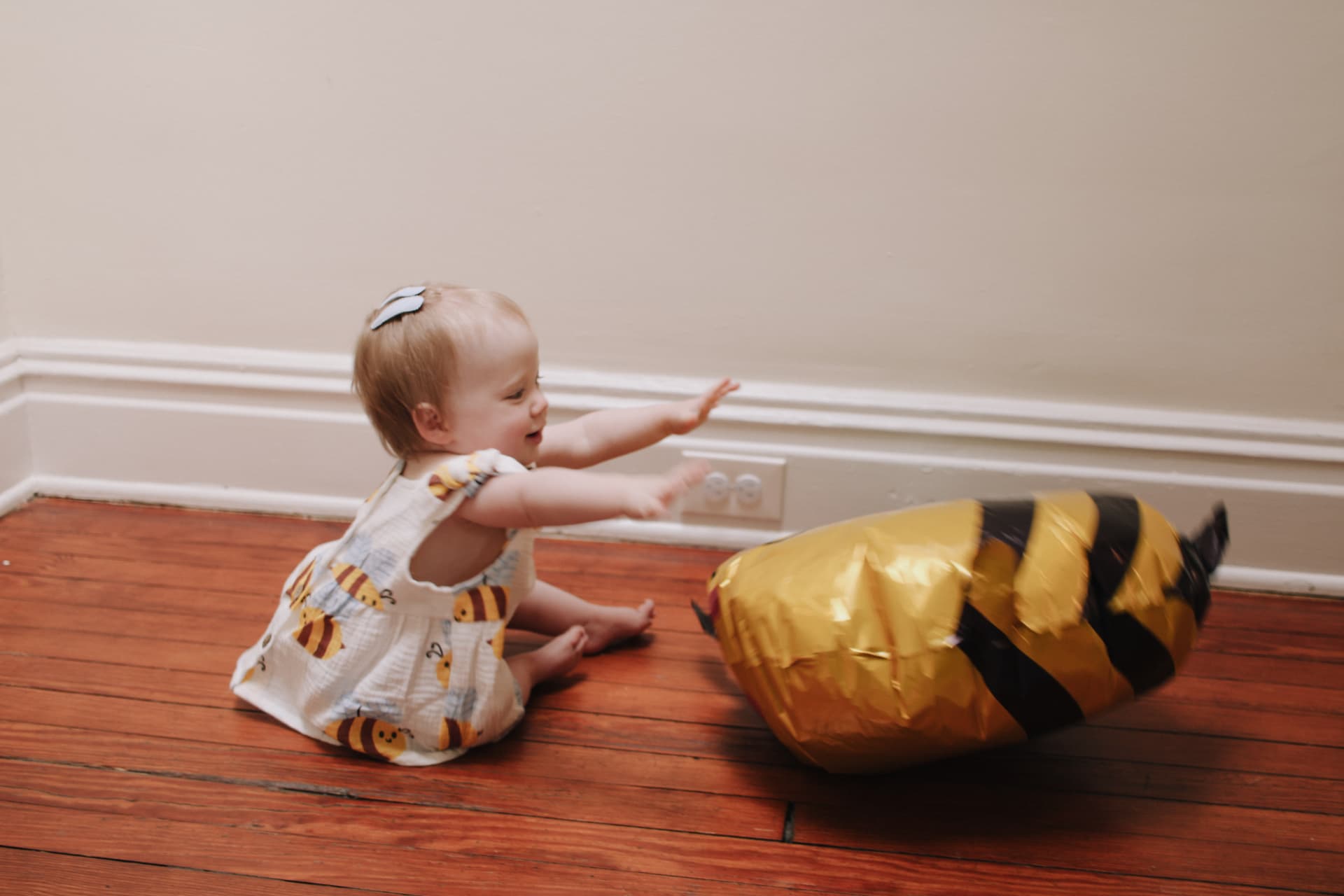 Phoebe reaching for a smiling bumblebee balloon