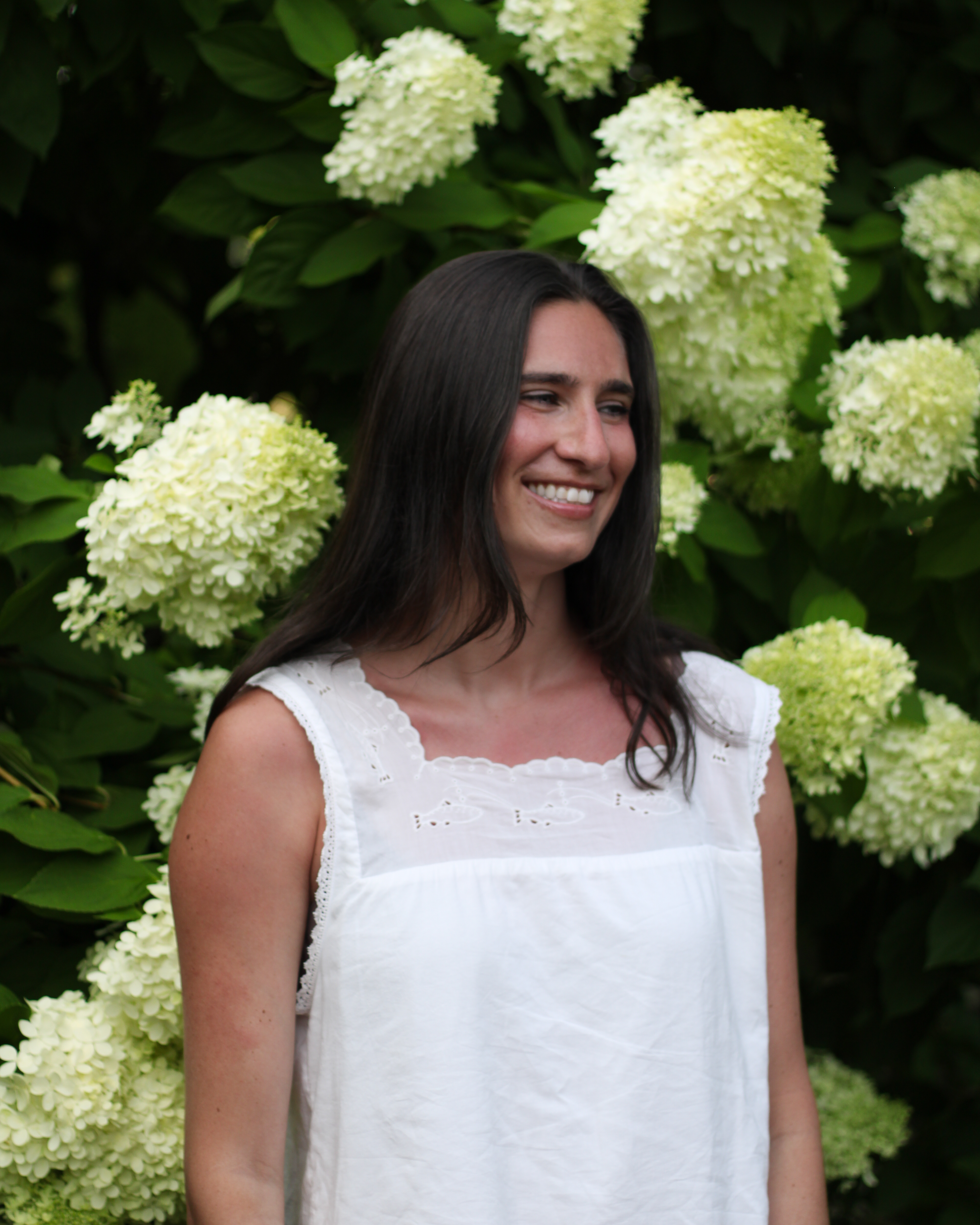 Sarah looking off to the side beside a hydrangea bush