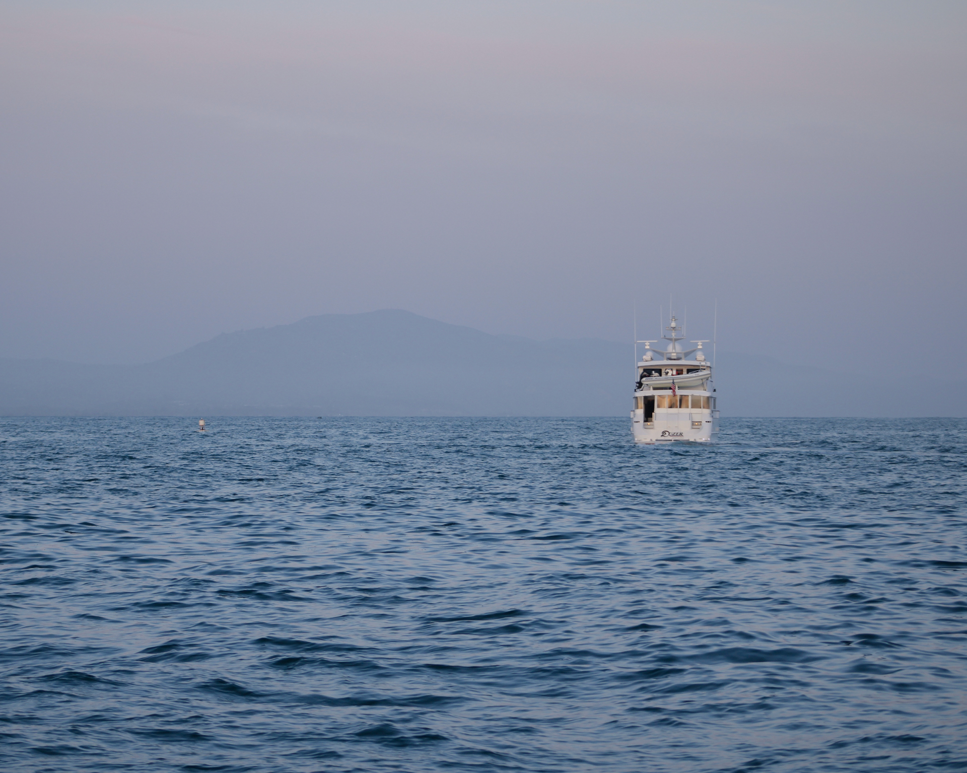A white yacht anchored on calm blue water off the Santa Barbara coast at dusk