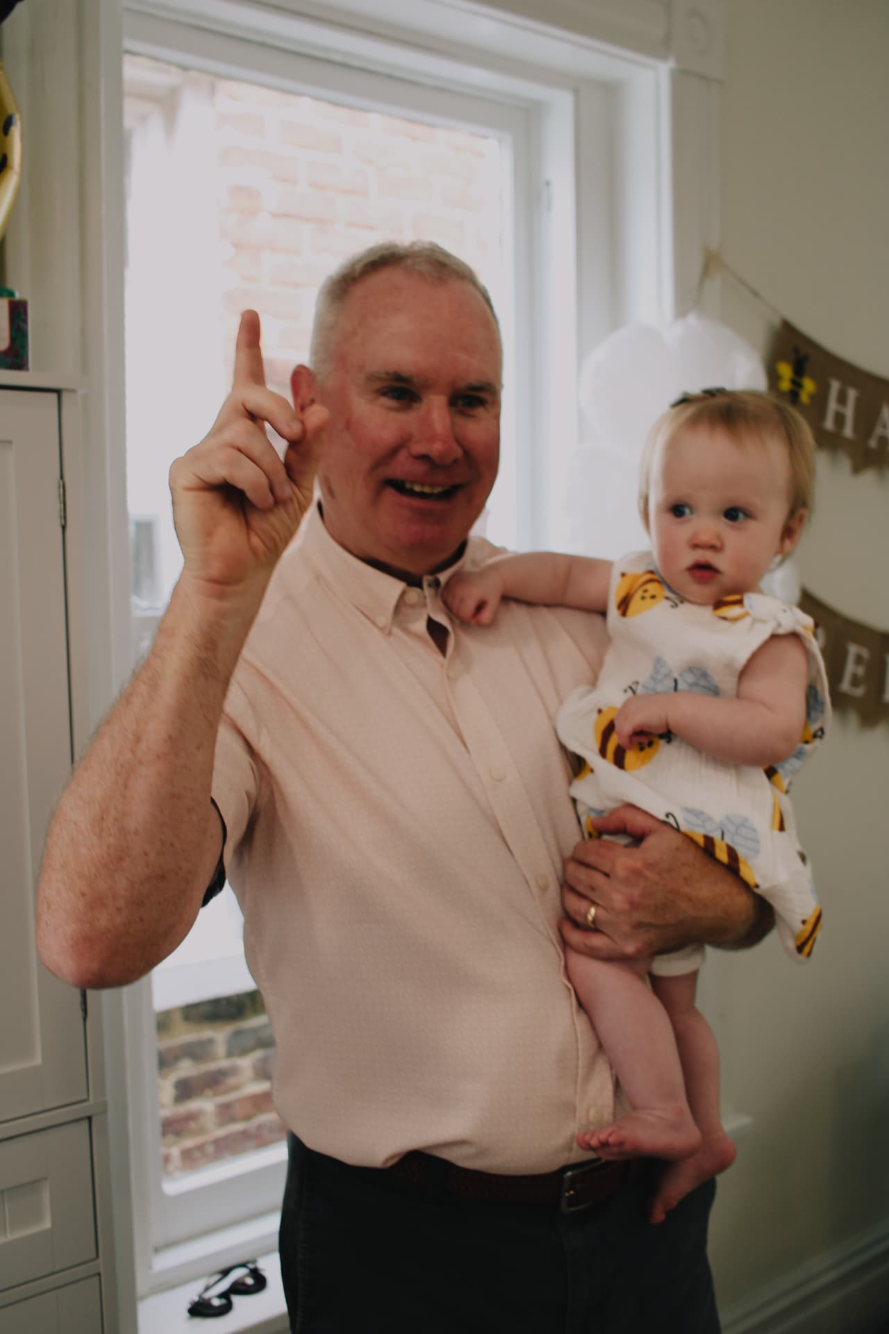 Phoebe held by her grandpa holding up one finger