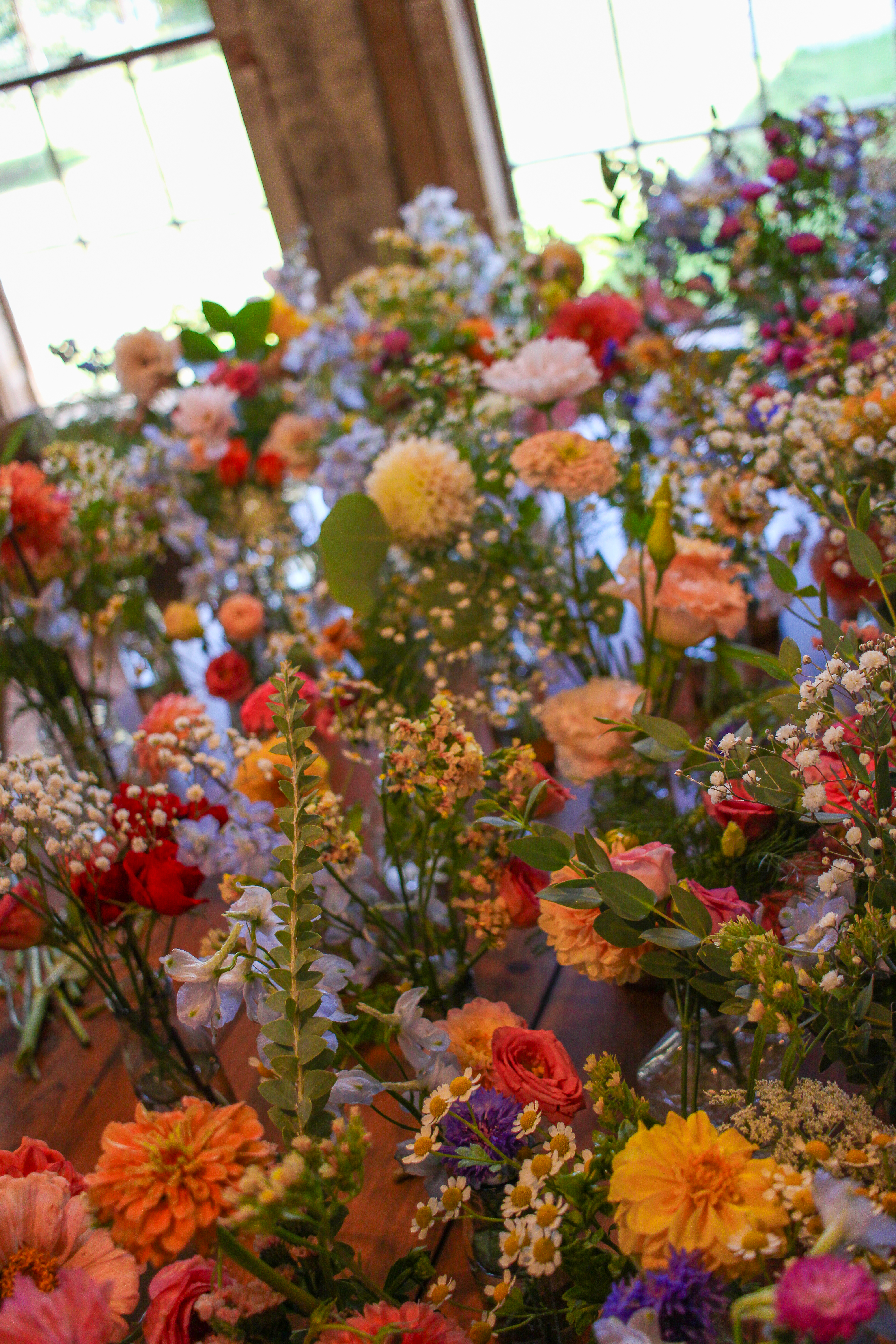 Overhead view of dozens of colorful wildflower bouquets lined up by a barn window
