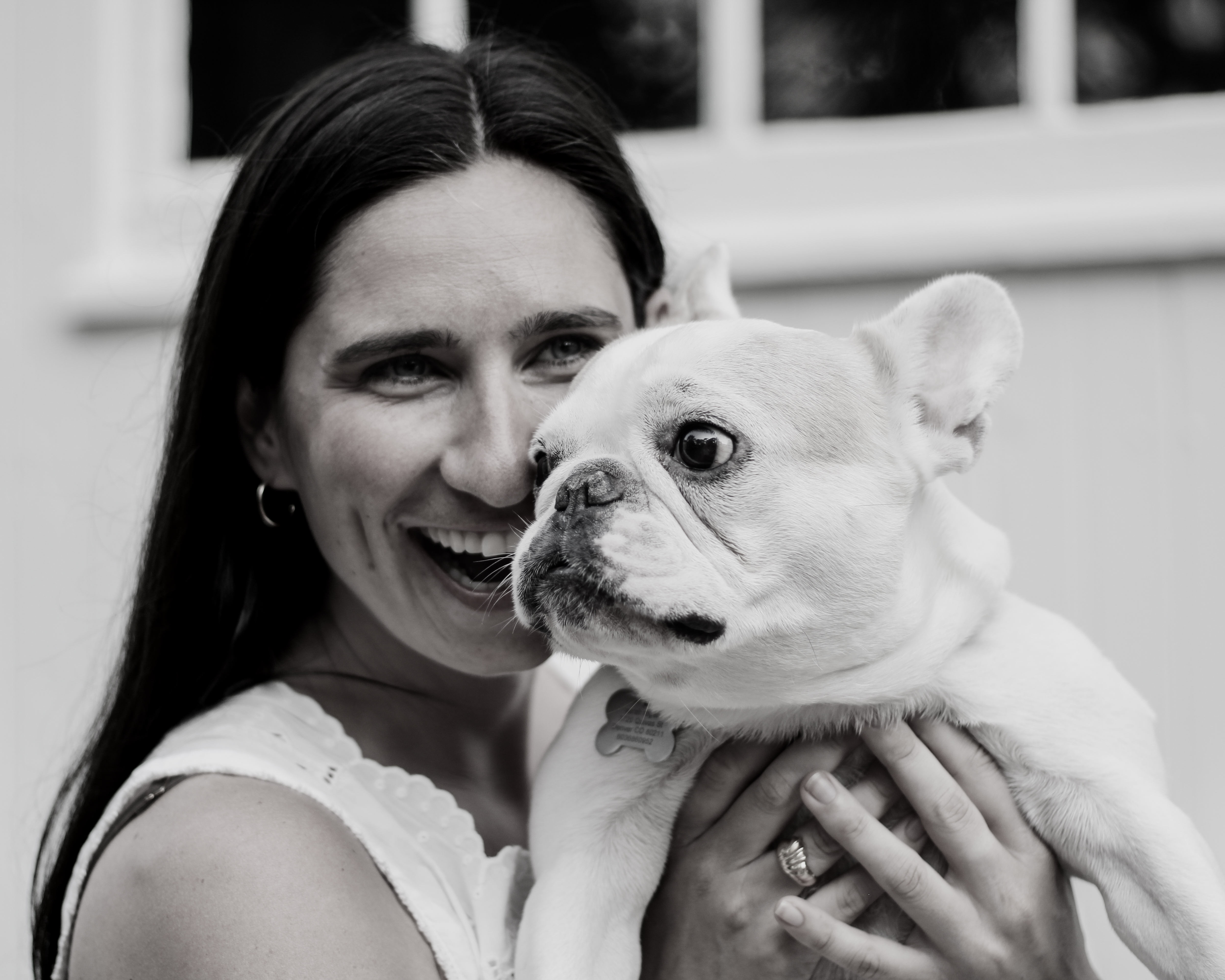 Black and white portrait of Sarah smiling with her French bulldog