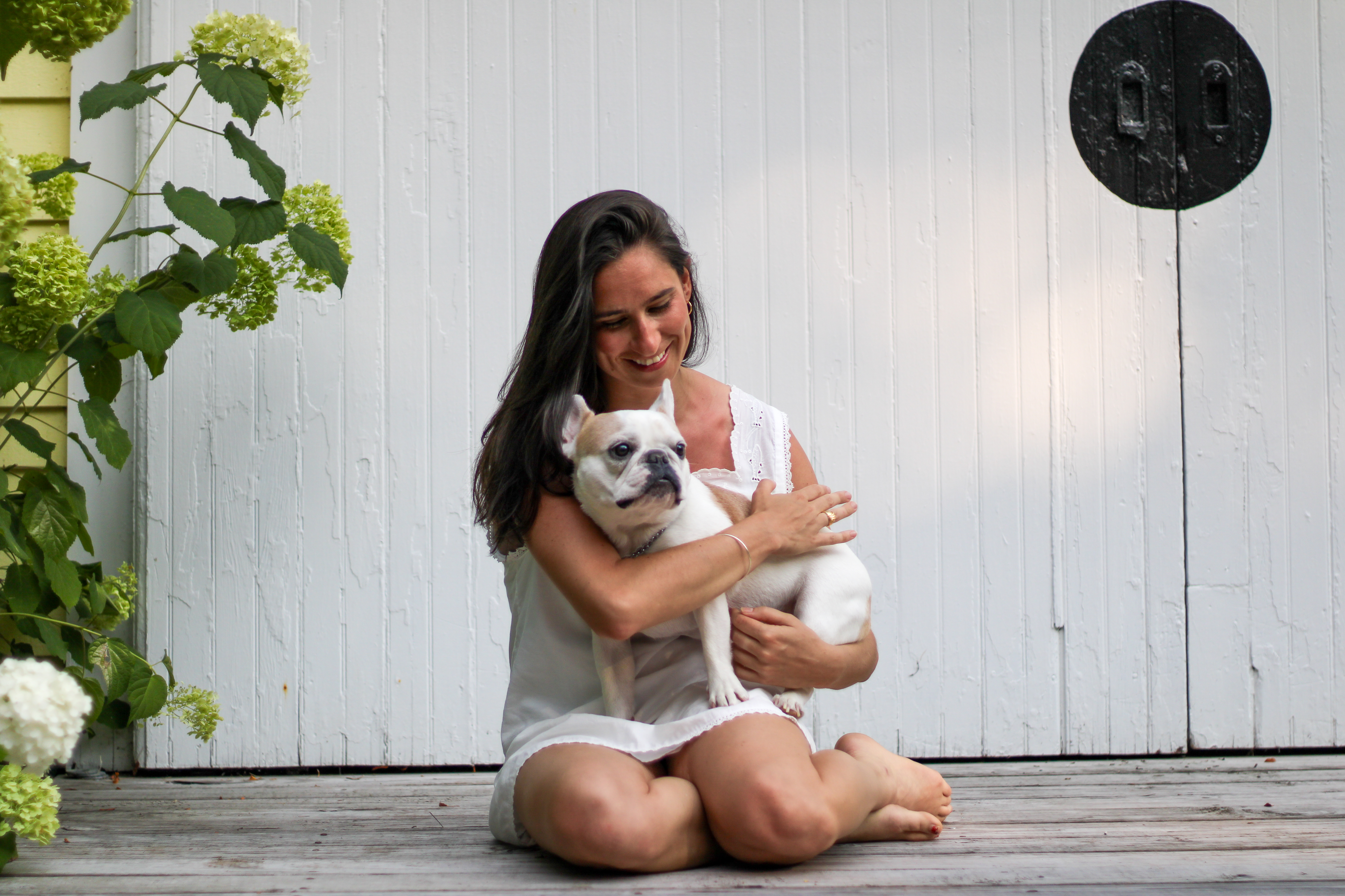 Sarah hugging her French bulldog in front of a white barn door