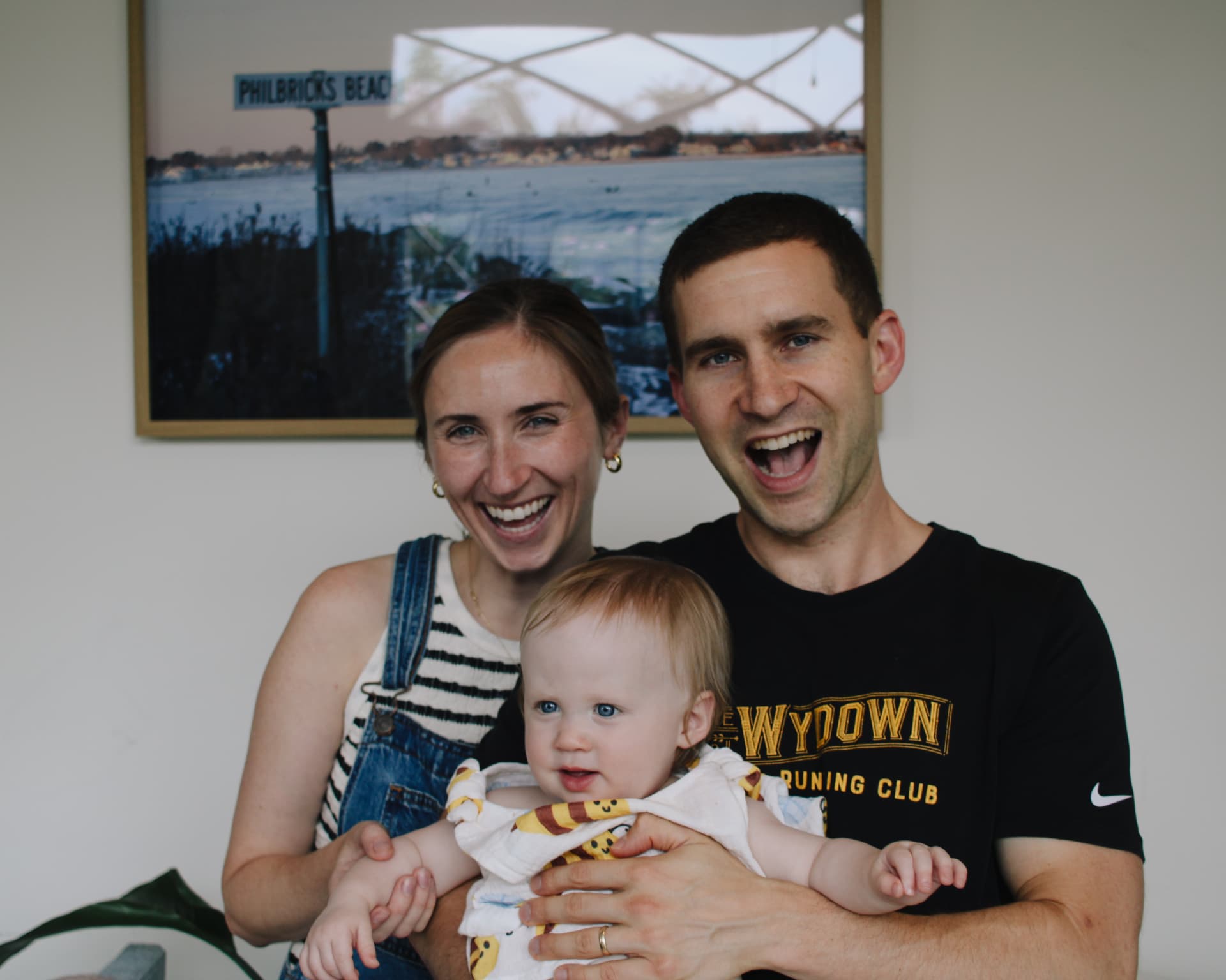 Phoebe with her parents in front of a framed Philbricks Beach print