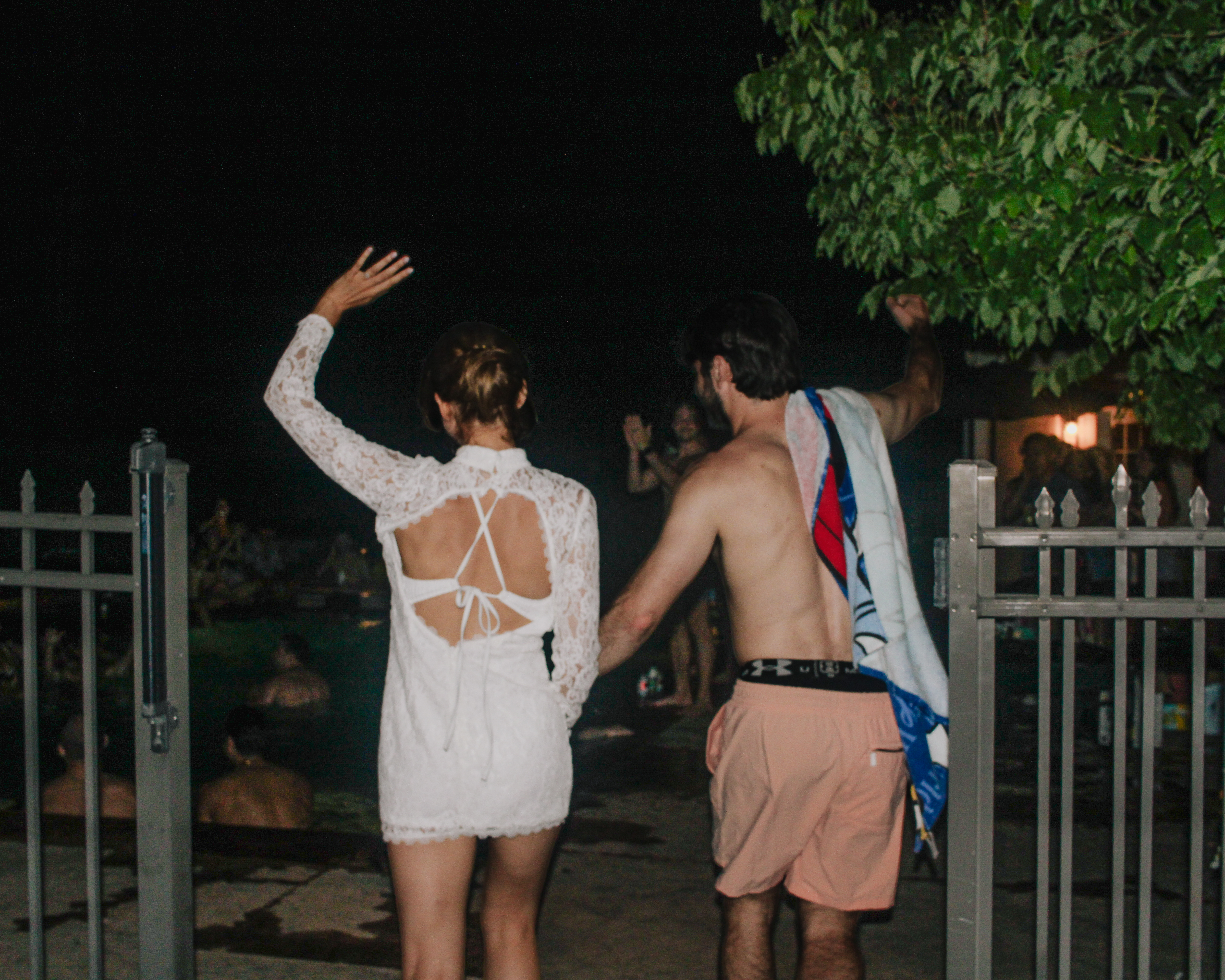 Caroline and Jamie waving as they walk through the pool gate at night