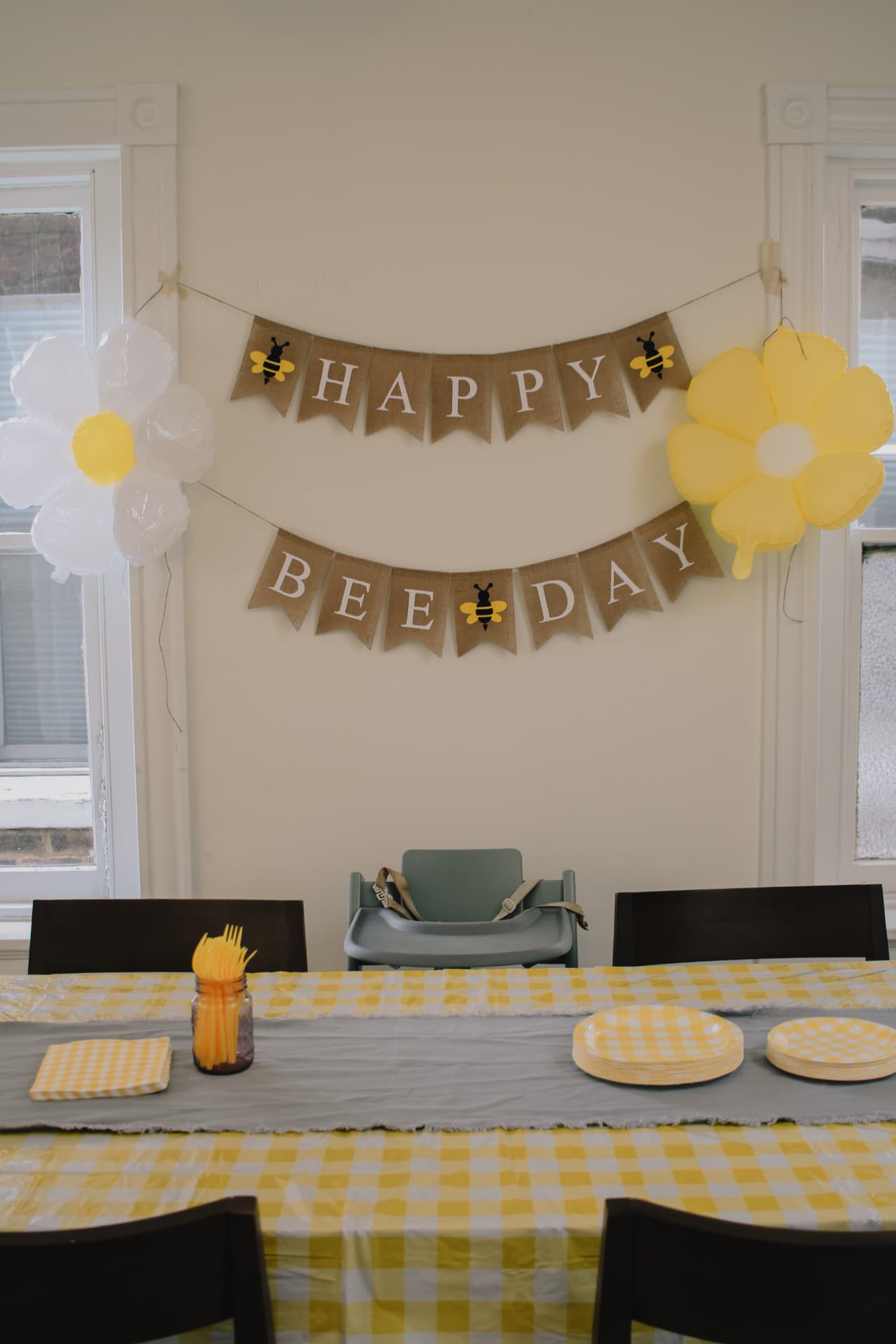 Happy Bee Day birthday table setup with yellow gingham and bumblebee banner