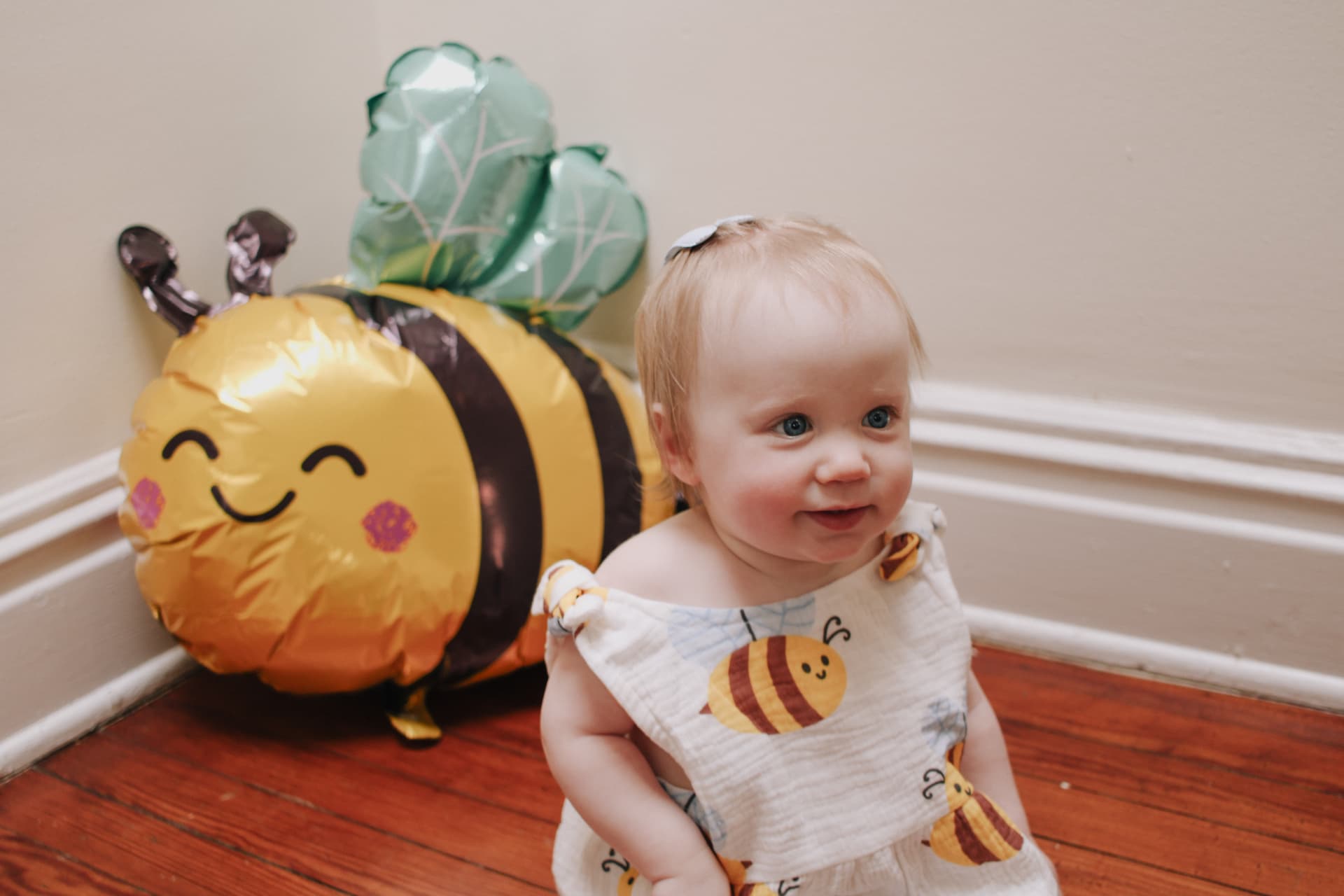Phoebe sitting next to a smiling bumblebee balloon