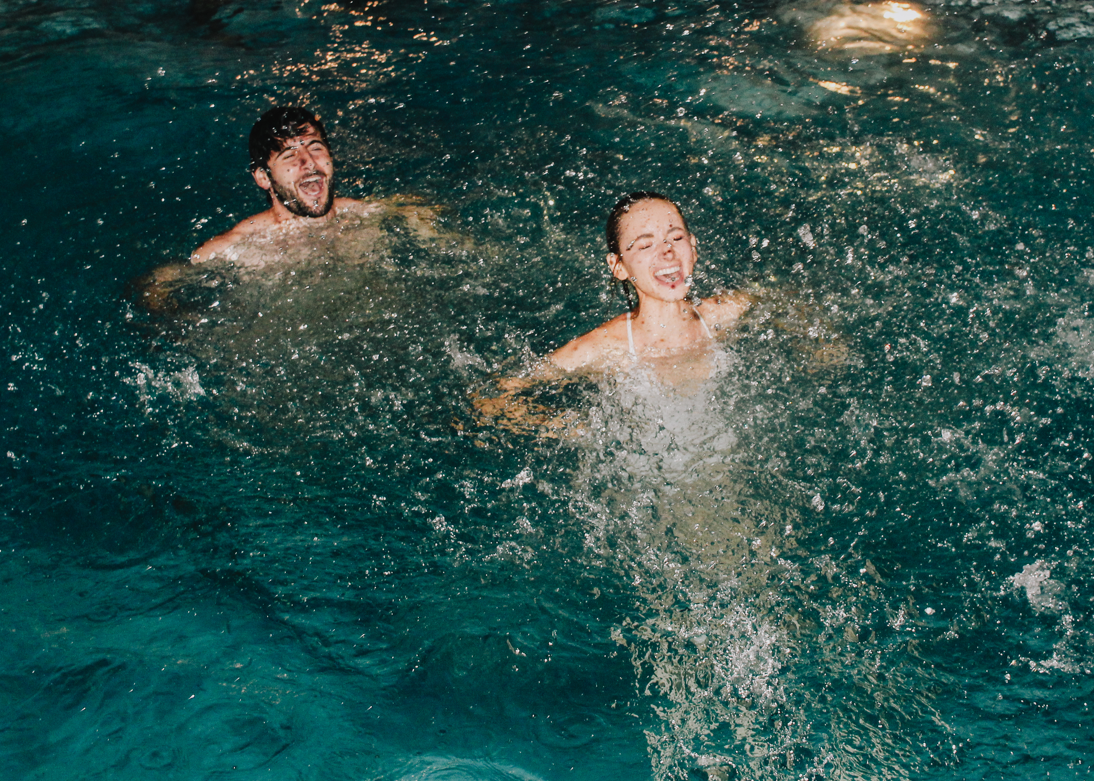 Caroline and Jamie laughing as they surface in the pool at night